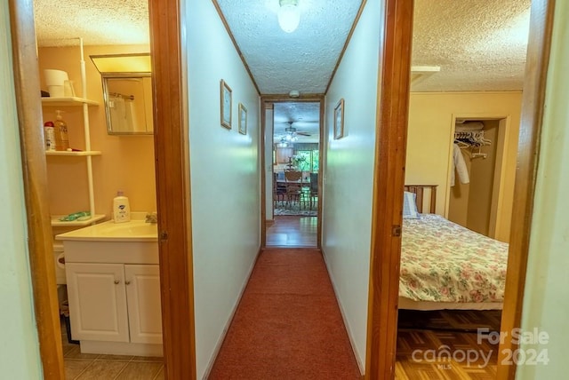 hallway featuring sink, a textured ceiling, and light colored carpet