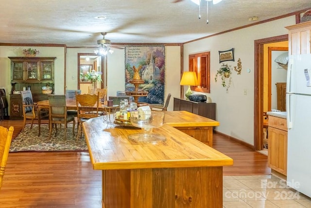 kitchen featuring ceiling fan, light hardwood / wood-style flooring, ornamental molding, butcher block counters, and white refrigerator