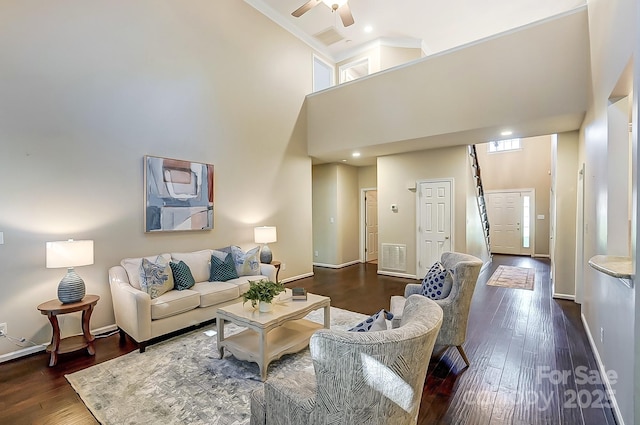 living room with ceiling fan, dark hardwood / wood-style flooring, and a high ceiling