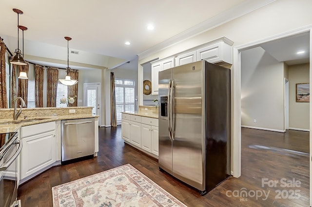 kitchen featuring light stone countertops, white cabinetry, sink, stainless steel appliances, and pendant lighting