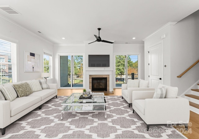 living room with light hardwood / wood-style floors, ornamental molding, a wealth of natural light, and ceiling fan