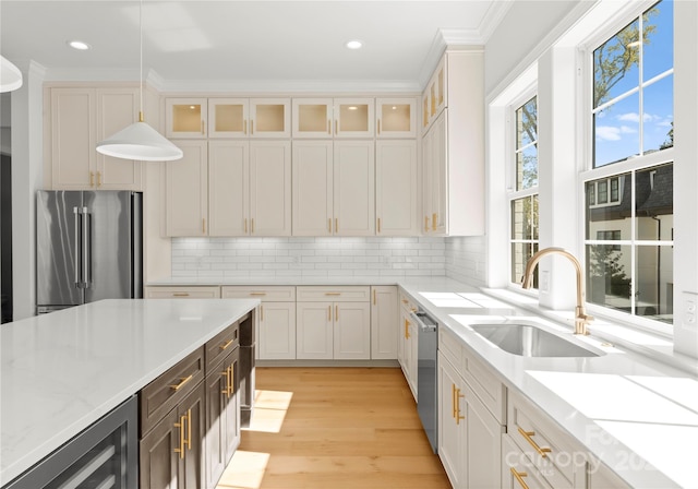 kitchen featuring appliances with stainless steel finishes, white cabinetry, pendant lighting, crown molding, and sink