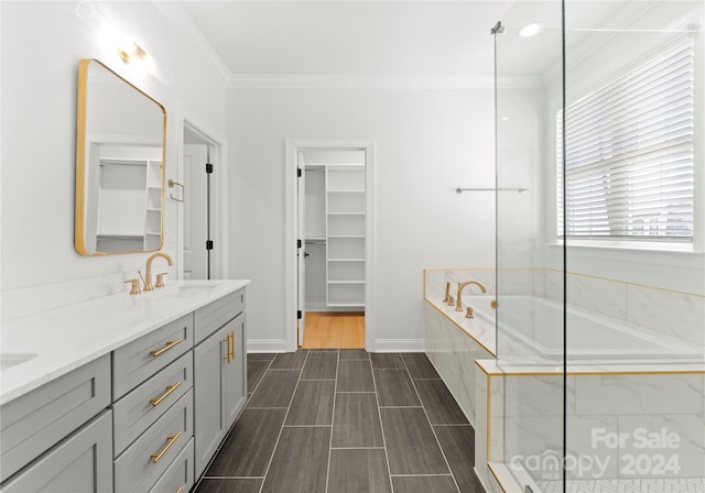 bathroom featuring vanity, ornamental molding, and tiled bath