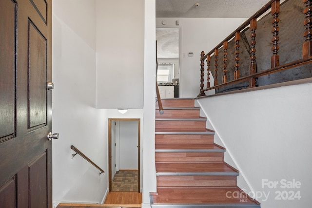 staircase featuring hardwood / wood-style floors and a textured ceiling