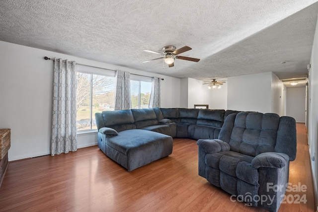 living room featuring ceiling fan, hardwood / wood-style flooring, and a textured ceiling