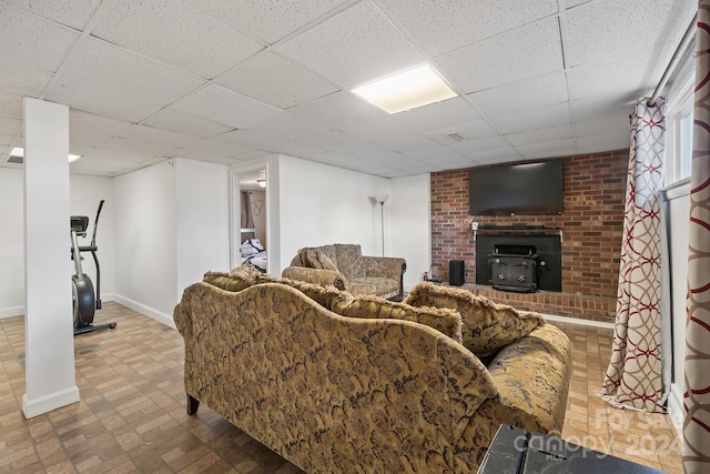 living room featuring a wood stove and a drop ceiling