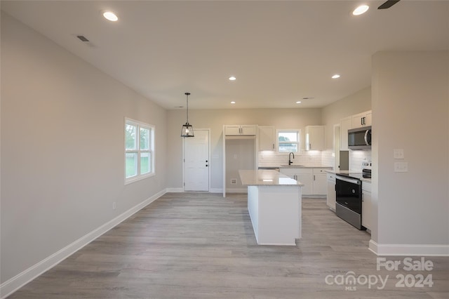 kitchen featuring a wealth of natural light, a center island, white cabinetry, and appliances with stainless steel finishes