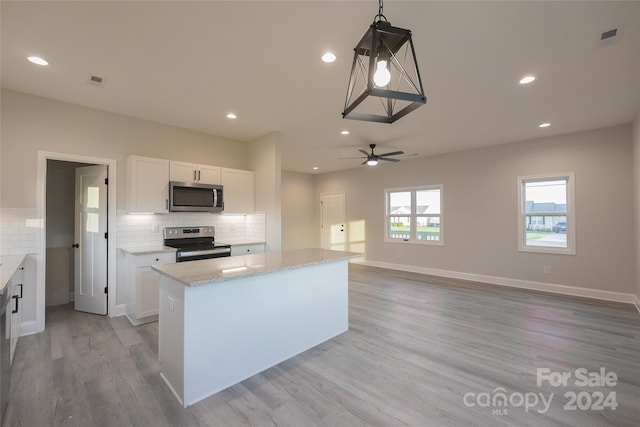 kitchen with decorative light fixtures, a center island, white cabinetry, and appliances with stainless steel finishes