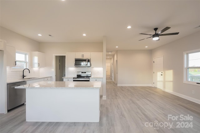 kitchen featuring white cabinetry, plenty of natural light, a kitchen island, and appliances with stainless steel finishes