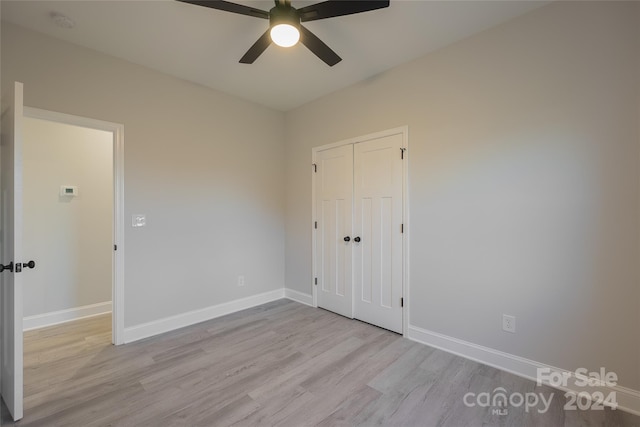 unfurnished bedroom featuring ceiling fan, light wood-type flooring, and a closet