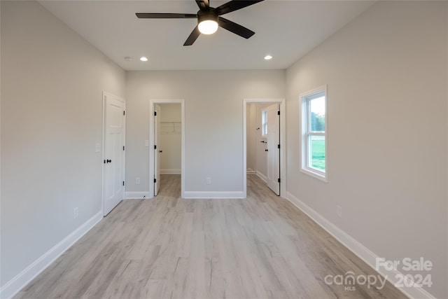 unfurnished bedroom with ceiling fan, light hardwood / wood-style floors, a walk in closet, and a closet