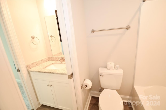 bathroom featuring toilet, hardwood / wood-style floors, vanity, and a bathtub