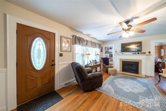 416 W Main St, Mooresboro, NC 28114 - entrance foyer featuring plenty of natural light, a wainscoted wall, ceiling fan, wood finished floors, and a fireplace with flush hearth