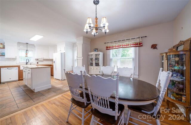 dining room with sink, a notable chandelier, and light hardwood / wood-style flooring