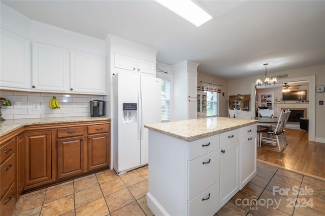 kitchen featuring decorative backsplash, a kitchen island, white refrigerator with ice dispenser, pendant lighting, and white cabinets