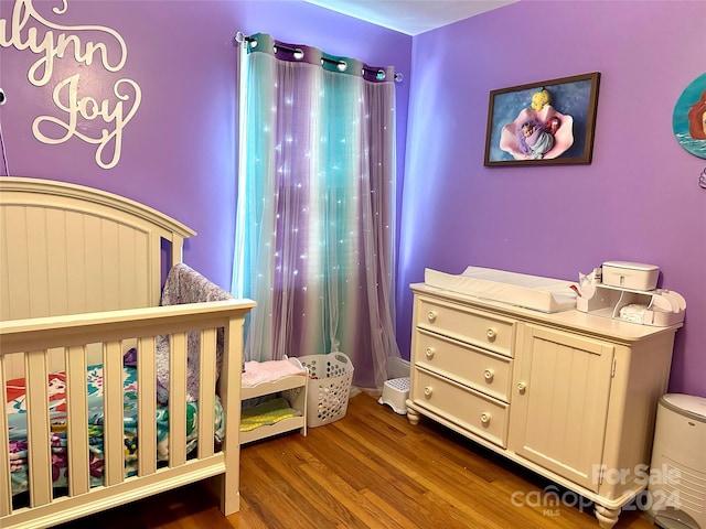 bedroom featuring a nursery area and hardwood / wood-style flooring