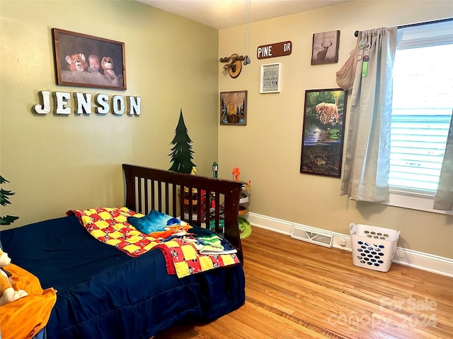 bedroom with multiple windows and hardwood / wood-style floors