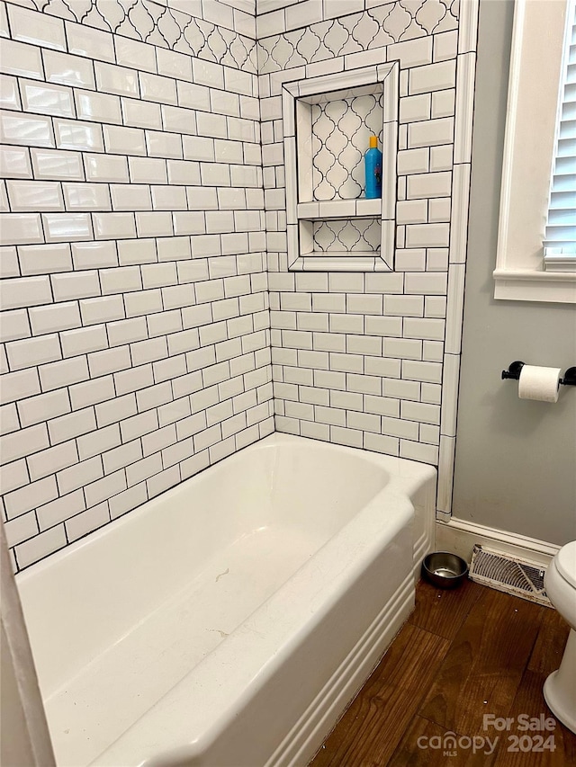 bathroom with toilet, tiled shower / bath, and hardwood / wood-style flooring