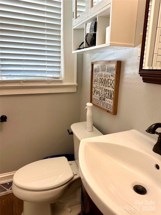 bathroom with toilet, sink, and plenty of natural light