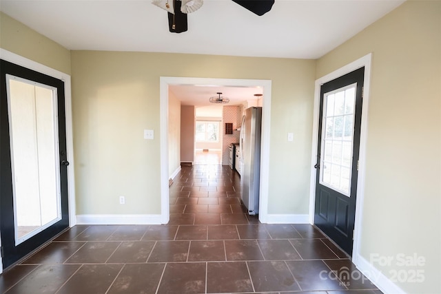 foyer with a wealth of natural light, ceiling fan, and dark tile patterned flooring