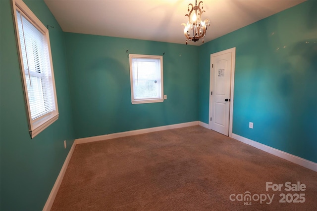 spare room with carpet flooring and a notable chandelier