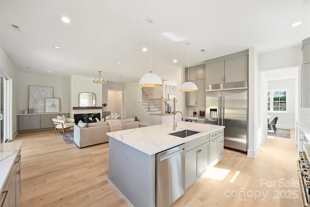 571 Lyttleton Dr, Charlotte, NC 28211 - kitchen with gray cabinets, light stone counters, a sink, light wood-type flooring, and stainless steel appliances