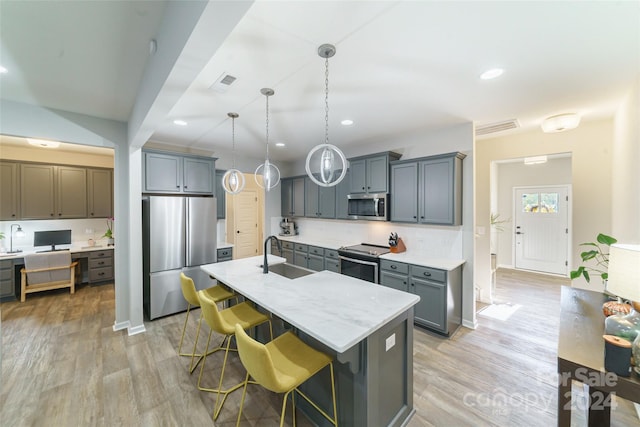 kitchen featuring hanging light fixtures, a center island with sink, sink, a kitchen bar, and appliances with stainless steel finishes