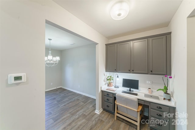 office space featuring built in desk, dark hardwood / wood-style flooring, and a chandelier