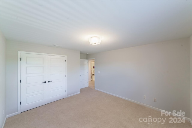 unfurnished bedroom with light carpet and a closet