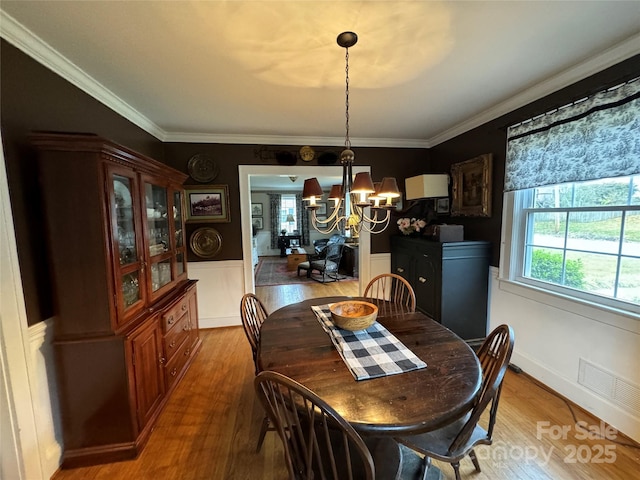 dining area with hardwood / wood-style floors, crown molding, and a chandelier