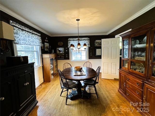 dining space featuring crown molding, light hardwood / wood-style flooring, and a notable chandelier