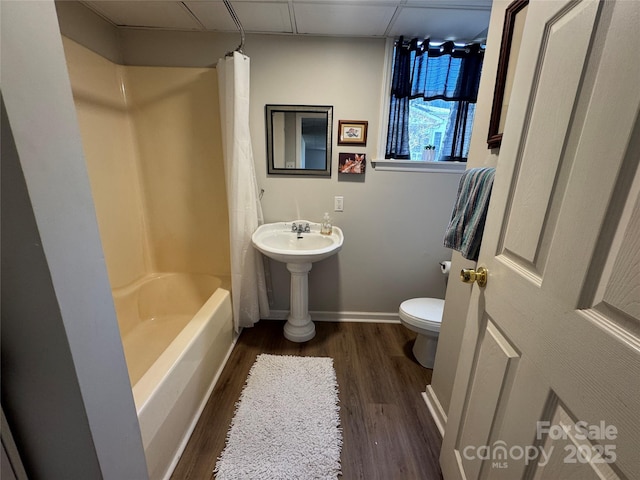 bathroom featuring shower / tub combo with curtain, wood-type flooring, toilet, and a drop ceiling