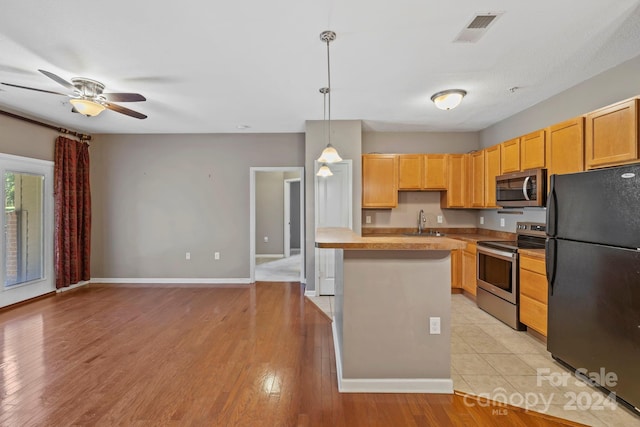 kitchen featuring sink, hanging light fixtures, ceiling fan, stainless steel appliances, and light hardwood / wood-style flooring