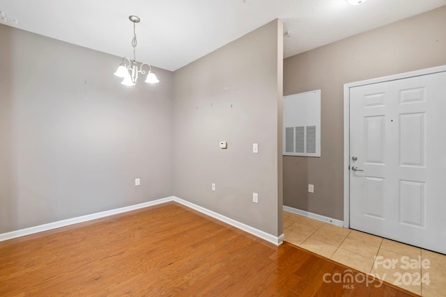 empty room featuring a chandelier and hardwood / wood-style floors