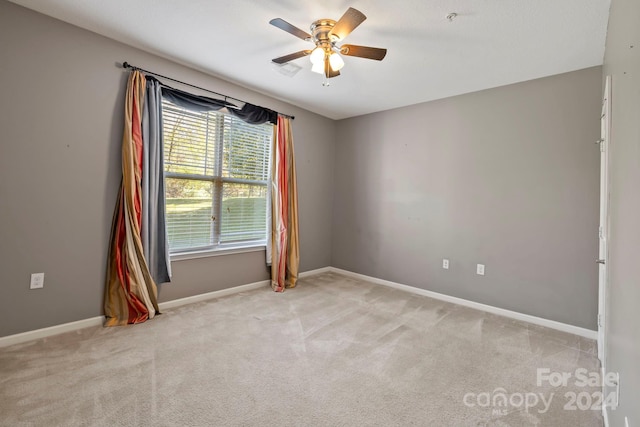 spare room with ceiling fan and light colored carpet