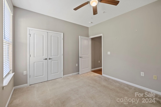 unfurnished bedroom with a closet, ceiling fan, and light colored carpet