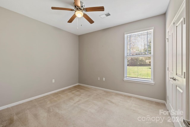 carpeted spare room with ceiling fan