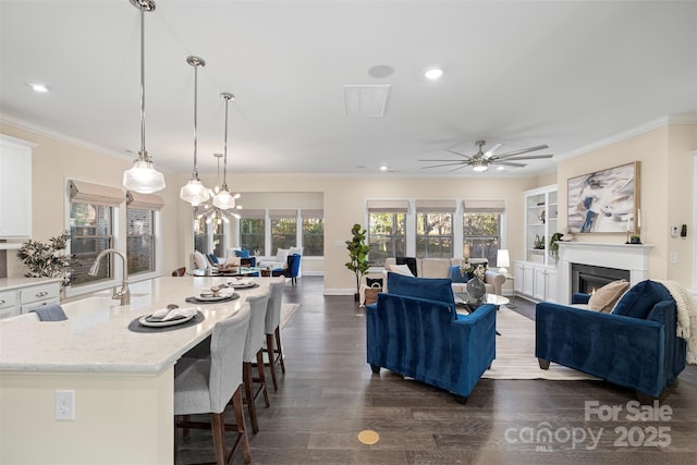 living room with ceiling fan, dark wood-type flooring, sink, and ornamental molding