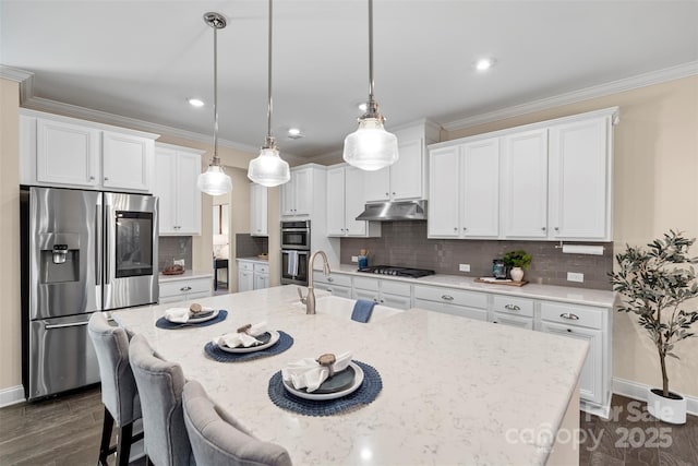 kitchen featuring stainless steel appliances, pendant lighting, white cabinetry, and a kitchen island with sink