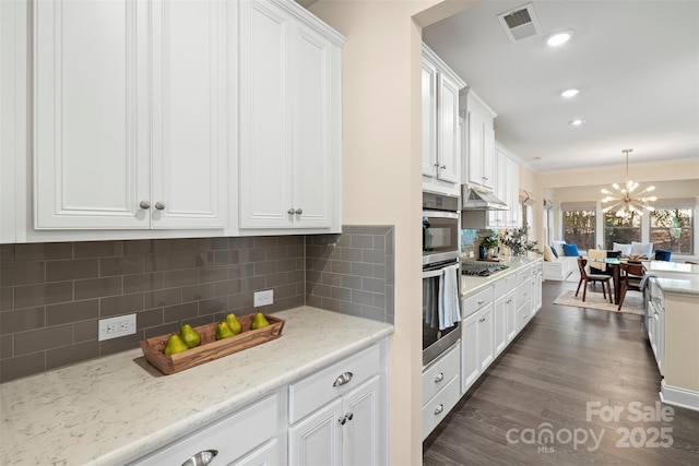 kitchen with white cabinetry, backsplash, stainless steel gas stovetop, and pendant lighting