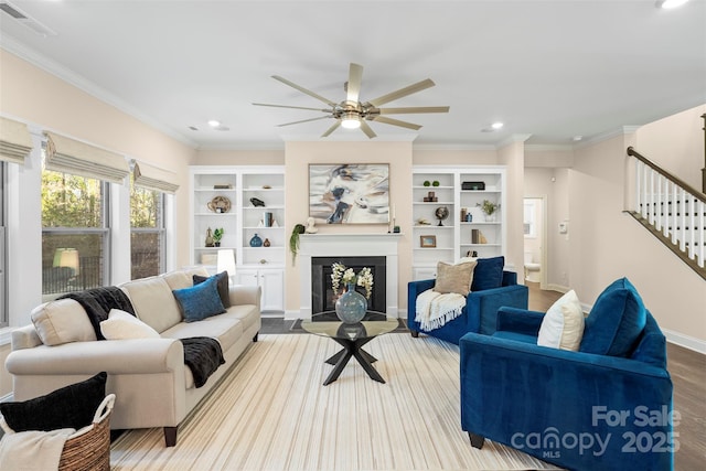 living room featuring ceiling fan, ornamental molding, and light wood-type flooring