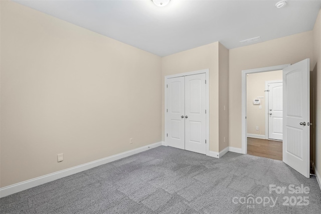 unfurnished bedroom with light colored carpet and a closet