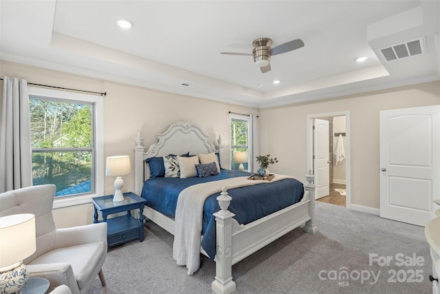 bedroom featuring ceiling fan, multiple windows, connected bathroom, and a raised ceiling