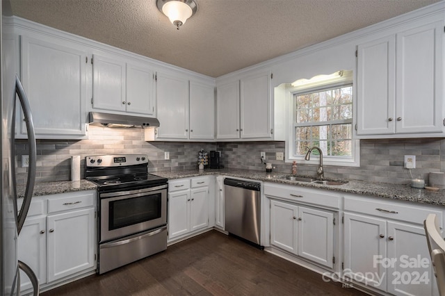 kitchen with stainless steel appliances, white cabinetry, sink, light stone countertops, and dark hardwood / wood-style flooring