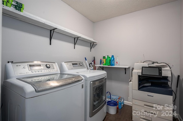 clothes washing area featuring a textured ceiling, washer and dryer, and dark hardwood / wood-style floors