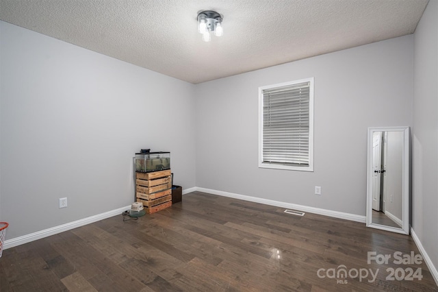 empty room with a textured ceiling and dark hardwood / wood-style floors