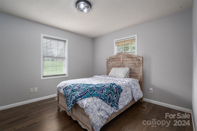 bedroom with a textured ceiling and dark hardwood / wood-style floors