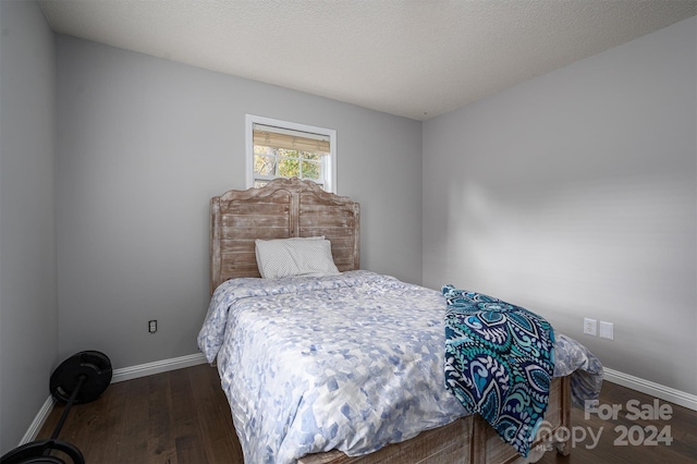 bedroom with a textured ceiling and dark hardwood / wood-style flooring