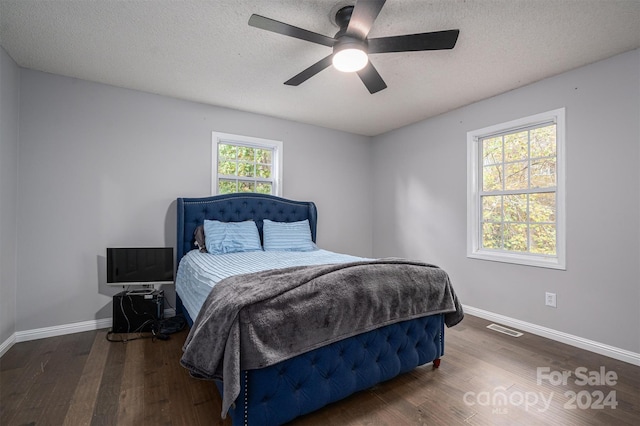 bedroom with dark hardwood / wood-style floors, ceiling fan, multiple windows, and a textured ceiling