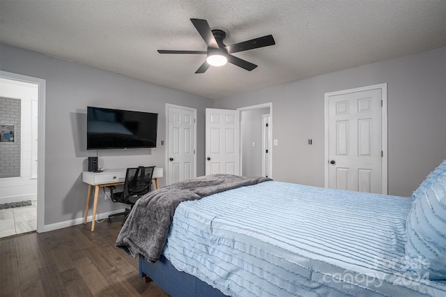 bedroom with a textured ceiling, dark wood-type flooring, ceiling fan, and connected bathroom